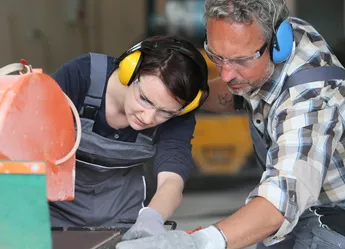 Worker showing apprentice new skills