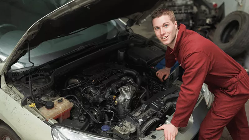 A mechanic looking under the bonnet of a car.