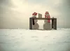 Two snowmen working at a desk in a snowy field
