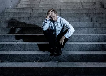 A man sitting on stone steps looking let down.
